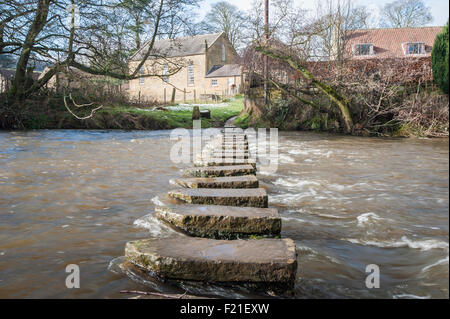 Pietre miliari attraverso un piccolo fiume in inglese villaggio rurale scena di campagna. Foto Stock