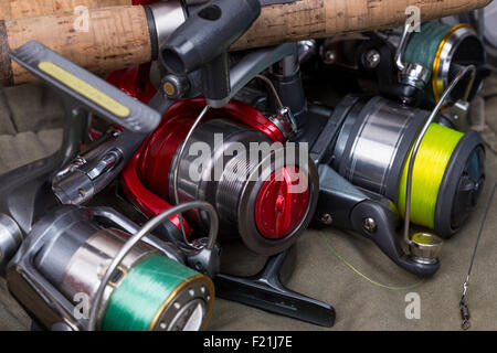 Mulinelli per la pesca con la linea diversi colori su sfondo di stoffa Foto Stock