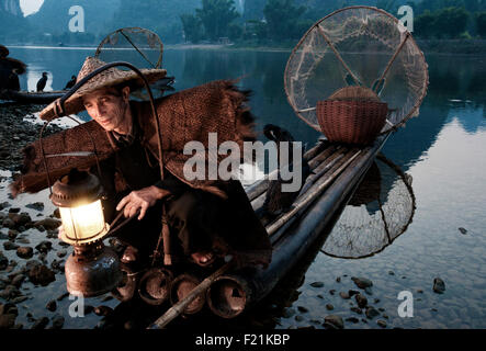 Cormorano fisherman accende una lanterna e prepara la sua zattera prima di uscire a pescare sul fiume Li e Yangshuo, Cina e Asia Foto Stock