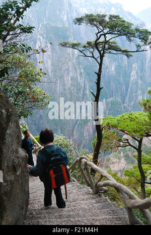 Matura coppia asiatica scendere passi concreti costruito nella roccia sul Xihai Grand Canyon Trail, gialle di montagna, Huangshan Foto Stock