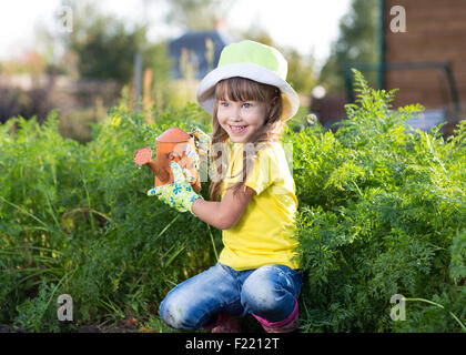 Bambina con irrigazione può nel giardino di verdure in un giorno di estate Foto Stock