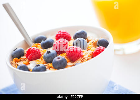 Una sana colazione con muesli, frutti di bosco freschi e succo di arancia. Profondità di campo, concentrarsi su bacche e muesli. Foto Stock