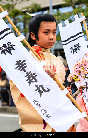 Festival di Genji p[sfilata in Giappone. Ragazzo, 8-10 anni, vestito come un maschio shirabyoshi ballerina dal periodo Heian e portante banner bianco. Foto Stock