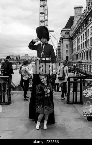 Un uomo vestito in uniforme protezioni mani volantini e pone per fotografie con i turisti, Londra, Inghilterra Foto Stock