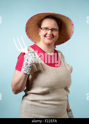 Donna matura, giardinaggio, studio shot, luce sfondo blu Foto Stock