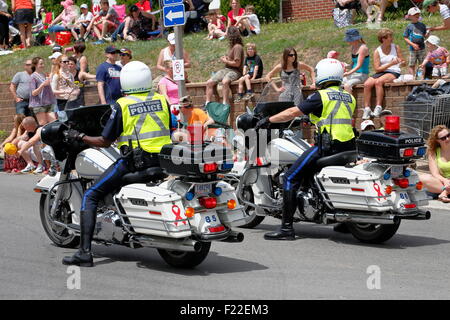 Due poliziotti uno bianco e uno nero sulla polizia motocicli accanto a una folla di persone far rispettare la legge e guardando Foto Stock