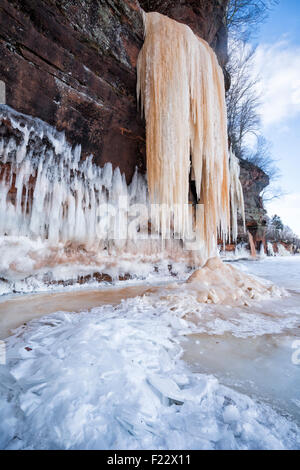 Arancione gigante ghiaccioli appesi da scogliere di arenaria sul lago Superiore, Apostolo Island National Lakeshore le grotte di ghiaccio, WI Foto Stock