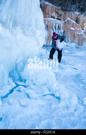 La donna solleva un grande pezzo pesante di ghiaccio mentre visitano le grotte di ghiaccio a Apostle Islands, Cornucopia, Wisconsin, STATI UNITI D'AMERICA Foto Stock