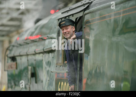 Treno a vapore conducente guardando fuori la sua cabina. Foto Stock