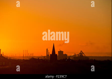 Set di sole sopra Redcar SSI industria acciaierie silouetted contro un bagliore arancione Foto Stock