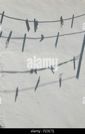 Ombre di pioli su linee di lavaggio su un muro bianco Foto Stock