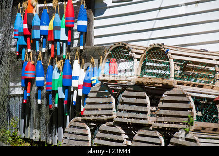 Varie trappole a base di aragosta e colorate galleggianti di legno utilizzati nella pesca commerciale industria Foto Stock