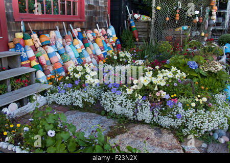 Molto colorato cortile anteriore con fiori luminosi miscelati con vari galleggianti, sfere di ormeggio e di lobster pot Foto Stock