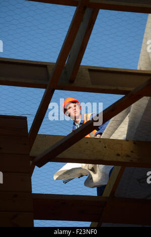 Un costruttore fissa fodera impermeabile carta al tetto di un grande edificio commerciale prima che il ferro si accende Foto Stock