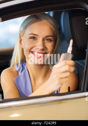 Donna felice getting chiave auto in auto show o salon Foto Stock