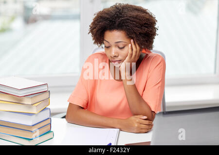 Annoiato americano africano donna facendo i compiti a casa Foto Stock