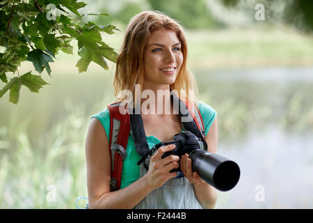 Donna felice con zaino e fotocamera all'aperto Foto Stock