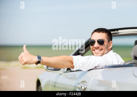 Felice uomo alla guida di auto e mostrando pollice in alto Foto Stock