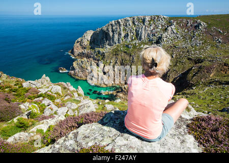 Il granito scogliere sul mare a Bosigran su Cornwall costa a Nord, Regno Unito, con una donna sat che si affaccia sul mare. Foto Stock