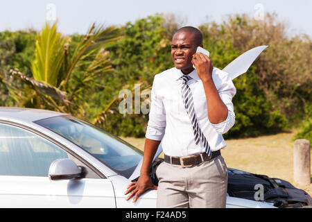 Preoccupato African American uomo con broken auto di chiamare per chiedere aiuto Foto Stock