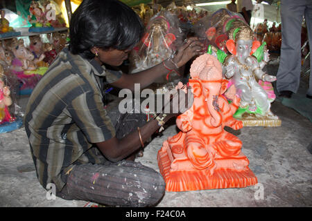 Un povero indiano artista dipinge un signore Ganesha idolo alla vigilia di Ganesh festival in India. Foto Stock
