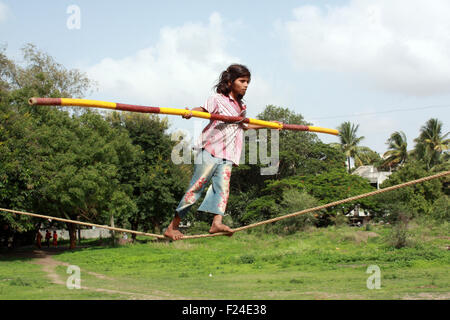 Una giovane povera ragazza trapezio saldi sulla sua corda e non i suoi trucchi per rendere un soggiorno in India. Foto Stock