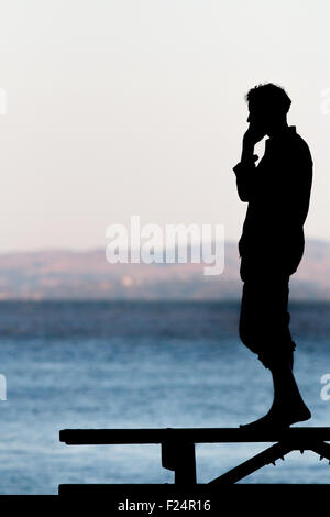 Uomo che parla sul cellulare vicino all'acqua Foto Stock