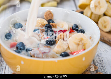 Corn flakes con frutta fresca e latte su un tavolo di legno Foto Stock