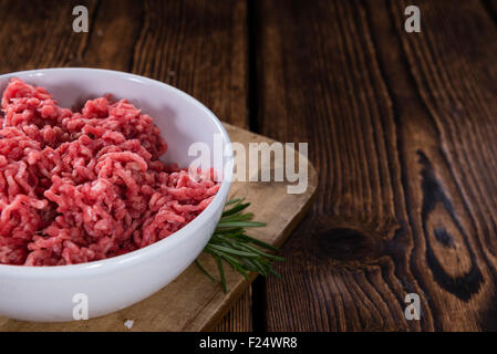 Carni macinate (carni bovine) come dettagliato di close-up shot su scuro dello sfondo in legno Foto Stock