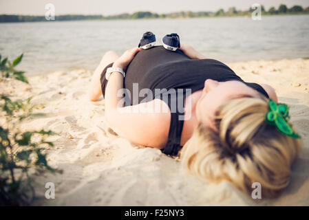 Foto di una donna in stato di gravidanza la pancia e minuscolo scarpe sulla sommità di esso. Foto Stock