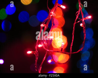 Una luce rossa delle lampadine stringa di filo sul fondale di altri colori di luce sfocate per la festa di Natale o Diwali decorazione. Foto Stock