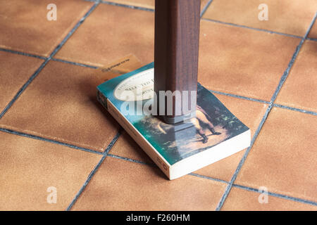 Gamba di un tavolo traballante supportato da un libro Foto Stock