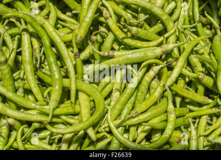 Pila di organico i peperoni verdi al mercato Foto Stock