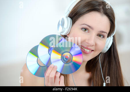 Donna con cuffie azienda CDs Foto Stock