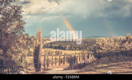 Arcobaleno e nuvole pesanti oltre il paesaggio toscano Foto Stock