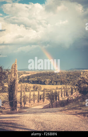 Arcobaleno e nuvole pesanti oltre il paesaggio toscano Foto Stock