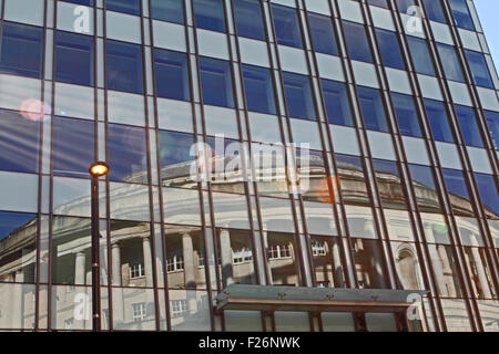 La riflessione della Biblioteca centrale di Manchester in un ufficio facciata di edificio Foto Stock