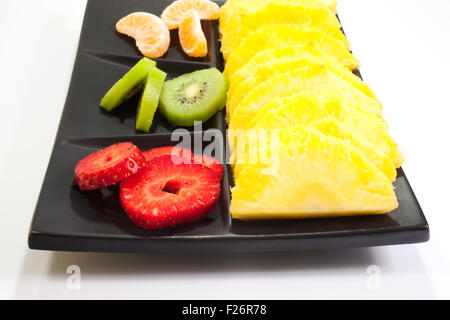 Frutta a fette su nero piattino Foto Stock