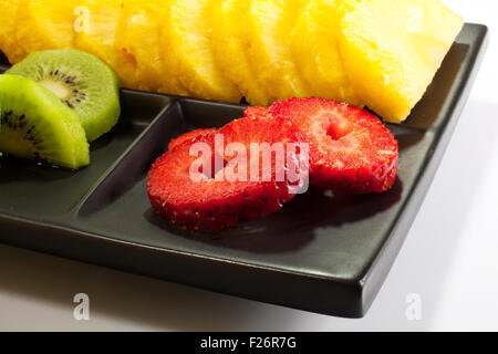 Frutta a fette su nero piattino Foto Stock