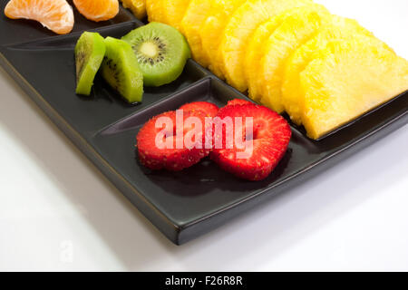 Frutta a fette su nero piattino Foto Stock