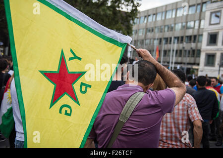 Un partecipante di una manifestazione contro la politica del governo turco, porta una bandiera del cosiddetto 'Persone della unità di protezione' (YPG), il principale servizio armato del curdo Comitato supremo, il governo del Kurdistan siriano, come si sfila per le strade di Stoccarda, Germania, 12 settembre 2015. Alcuni 2.000 curdi e il governo turco critici sono scesi in piazza per protestare contro l'escalation della tensione nel loro paese dopo la Turchia ha effettuato un ondata di scioperi contro il Partito dei Lavoratori del Kurdistan (PKK) bersagli nel nord Iraq. Foto: Wolfram Kastl/dpa Foto Stock