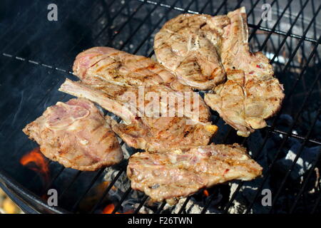 La cottura di una marinata di costolette di agnello su un barbecue Foto Stock