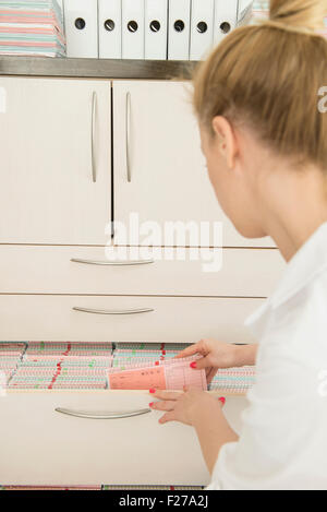 Medico donna ricerca per i record medici in un cassetto, Monaco di Baviera, Germania Foto Stock