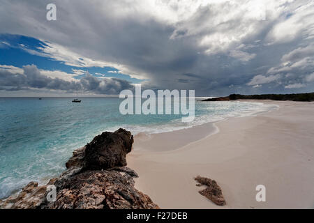 Moody spiaggia e barca a vela ancorata nella distanza, Cane Isola, Anguilla Foto Stock