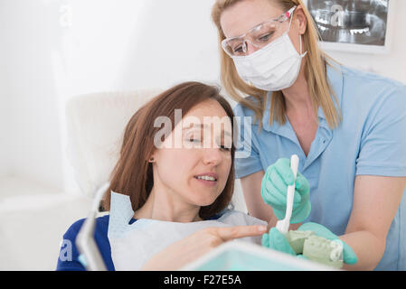 Assistente dentale per spiegare un paziente come spazzola denti, Monaco di Baviera, Germania Foto Stock