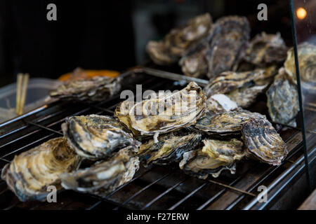 Ostriche su un grill, Miyajima, Hatsukaichi, Prefettura di Hiroshima, Giappone. Foto Stock