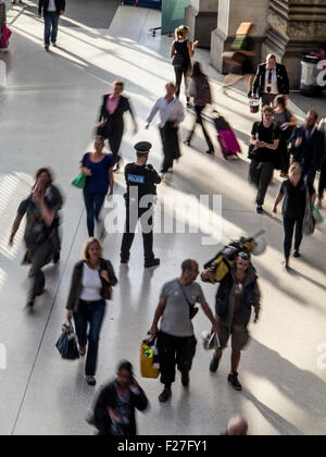 Un poliziotto solitario sta di guardia in un ora di punta alla stazione con i " commuters " correre da lui Foto Stock