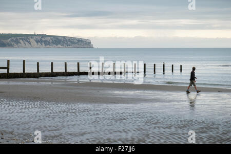 Un uomo che cammina sul lago spiaggia sull'Isola di Wight in Inghilterra Foto Stock