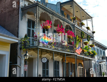 Un Creolo Townhouse ornato di balconi in ferro battuto, fiori appesi e bandiera arcobaleno, nel Quartiere Francese di New Orleans, LA Foto Stock