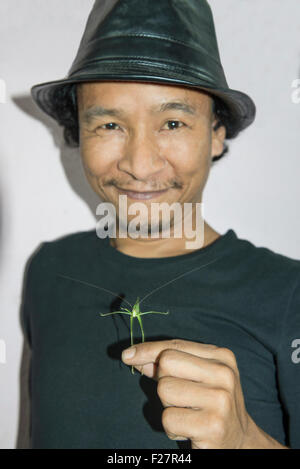 Ritratto di una metà uomo adulto holding grasshopper e sorridente, Nepal Foto Stock